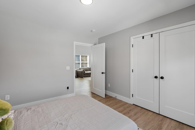 bedroom with light wood finished floors, baseboards, and a closet