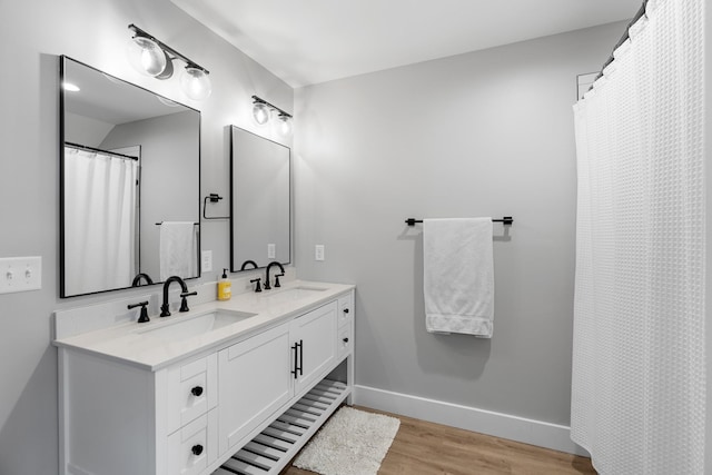 bathroom featuring double vanity, a sink, baseboards, and wood finished floors