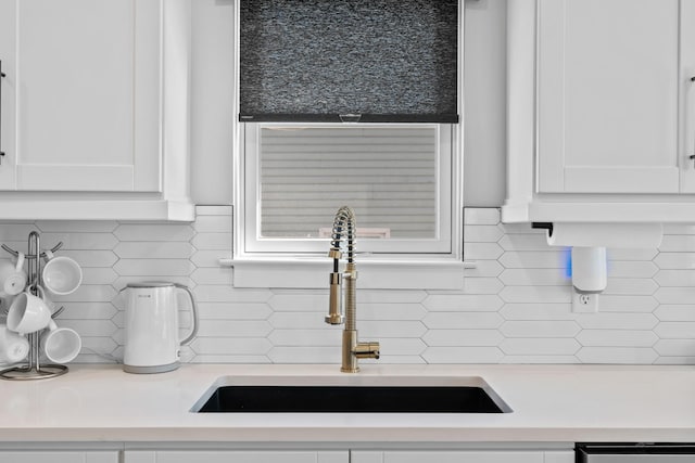 interior details with a sink, white cabinetry, light countertops, dishwasher, and tasteful backsplash