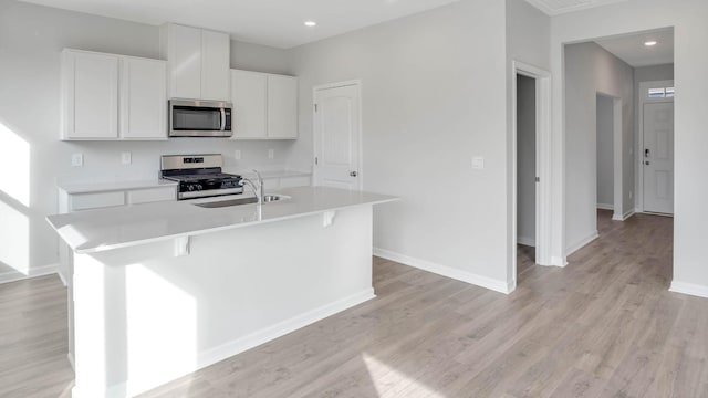 kitchen featuring stainless steel appliances, light countertops, a center island with sink, and white cabinets