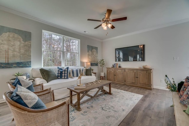 living room with a ceiling fan, light wood-style flooring, baseboards, and crown molding