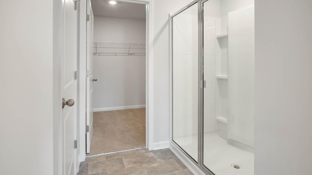 full bathroom featuring a shower stall, a spacious closet, and baseboards