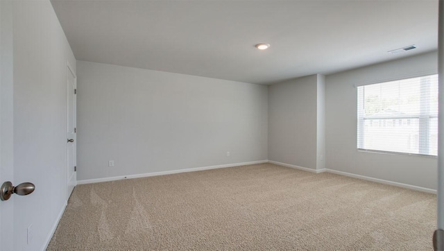 empty room featuring light carpet, visible vents, and baseboards