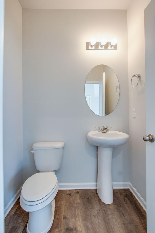 half bath featuring toilet, baseboards, and wood finished floors