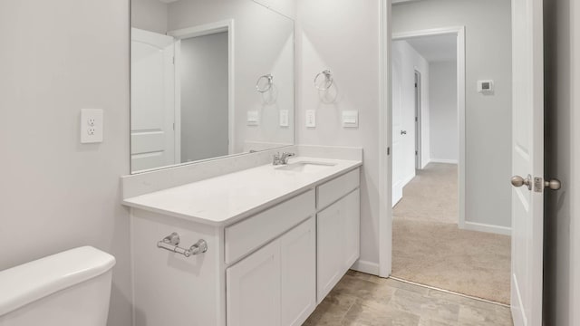 bathroom featuring toilet, baseboards, and vanity