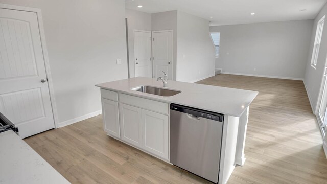 kitchen featuring an island with sink, white cabinets, stainless steel dishwasher, and light countertops