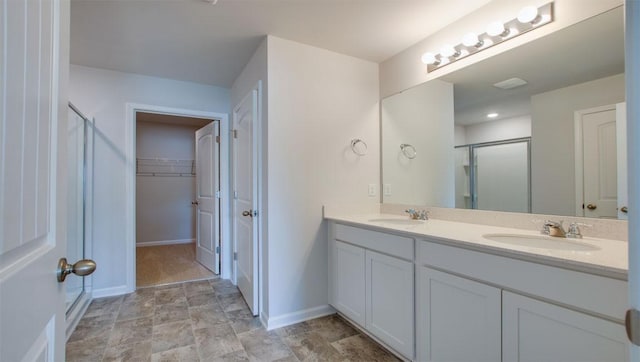 full bathroom featuring a spacious closet, double vanity, a sink, and a shower stall