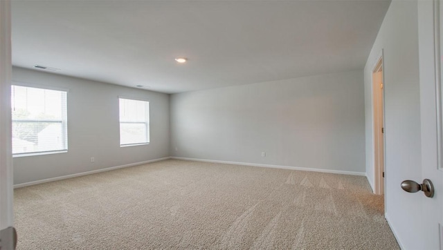 empty room featuring light carpet, visible vents, and baseboards