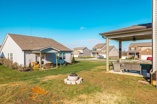 view of yard featuring a ceiling fan, a residential view, an outdoor living space with a fire pit, and a patio area