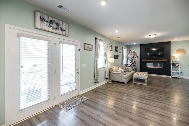 living area featuring a large fireplace, wood finished floors, visible vents, and baseboards