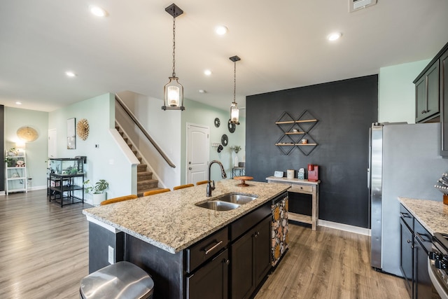 kitchen with light stone counters, a sink, and wood finished floors