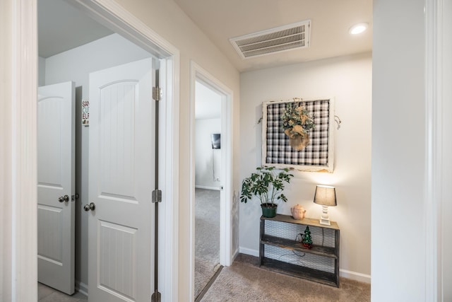 hall featuring carpet floors, visible vents, and baseboards