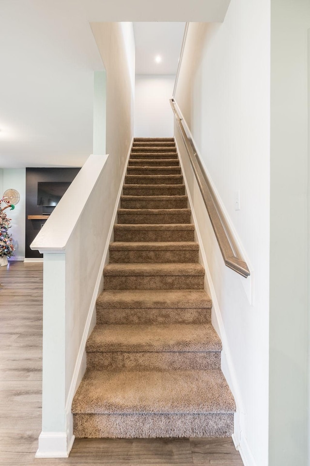 staircase featuring baseboards and wood finished floors