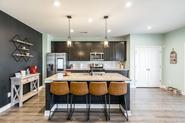 kitchen featuring stainless steel appliances, a sink, a center island with sink, and a kitchen breakfast bar