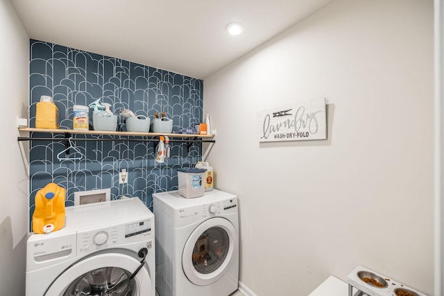 washroom featuring laundry area, washing machine and dryer, and an accent wall