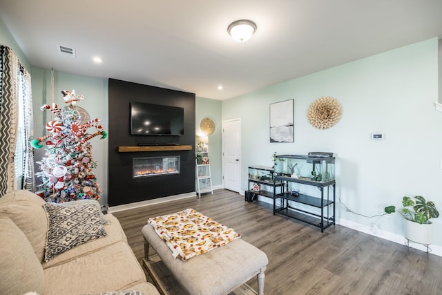 living area with a fireplace, wood finished floors, visible vents, and baseboards