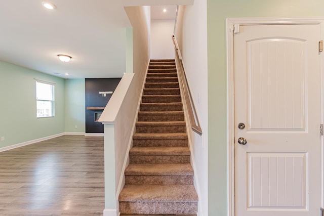 staircase featuring baseboards, wood finished floors, and recessed lighting