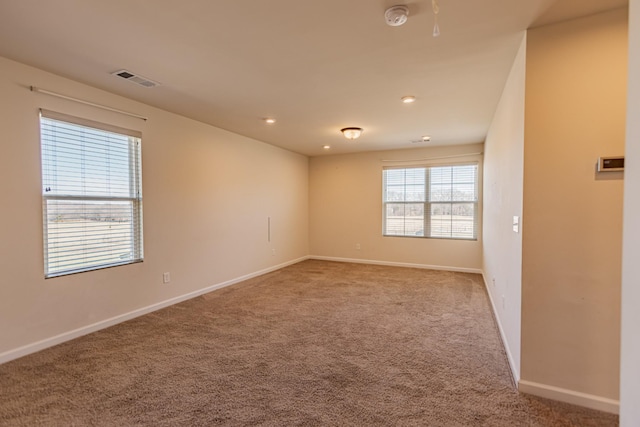 spare room featuring recessed lighting, carpet flooring, visible vents, and baseboards