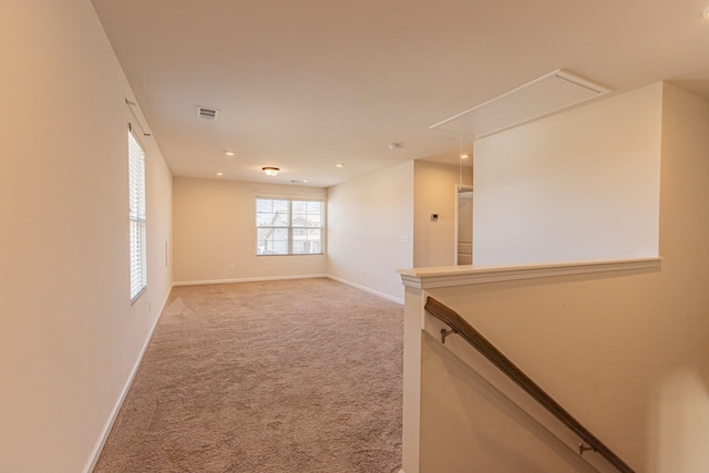 unfurnished room featuring light carpet, visible vents, attic access, and baseboards