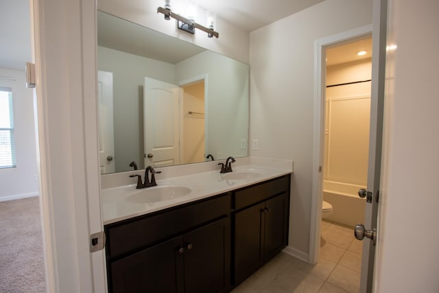 bathroom with toilet, double vanity, a sink, and tile patterned floors