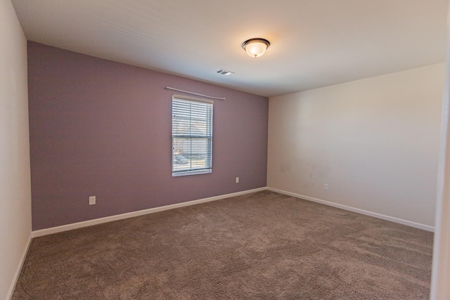 empty room with carpet, visible vents, and baseboards