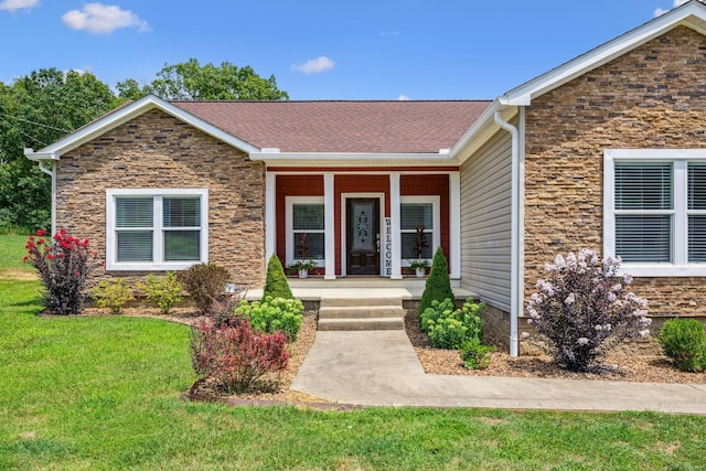 view of front facade with roof with shingles, a porch, and a front yard