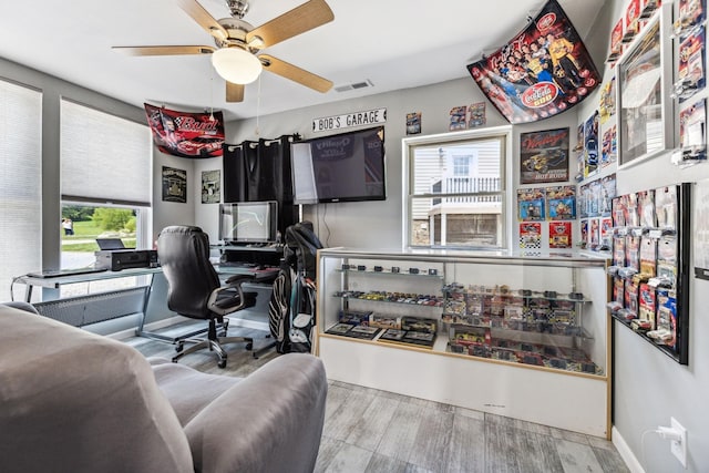 office space featuring light wood-style floors, visible vents, ceiling fan, and baseboards