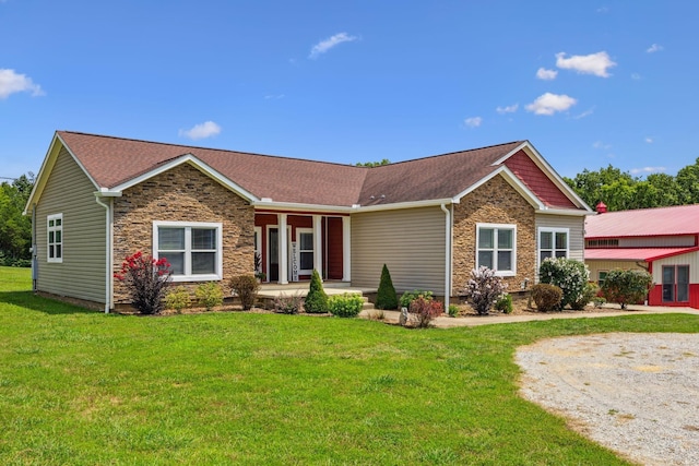 view of front of house featuring stone siding, a front yard, covered porch, and roof with shingles