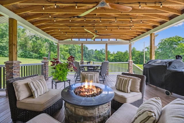 wooden deck with outdoor dining space, an outdoor living space with a fire pit, and area for grilling