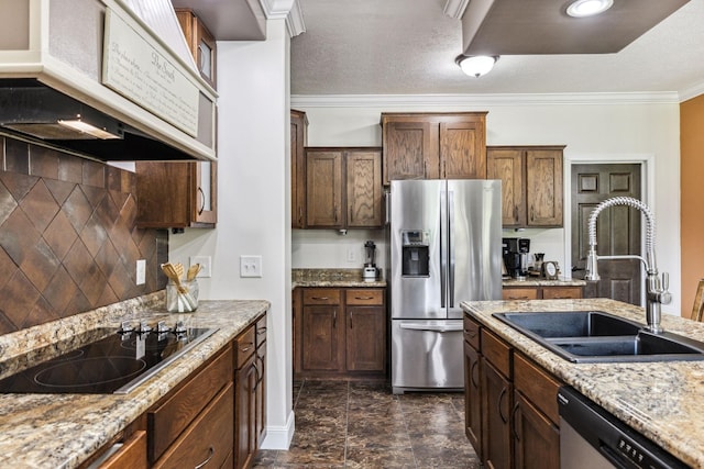 kitchen with appliances with stainless steel finishes, light stone countertops, custom exhaust hood, crown molding, and a sink