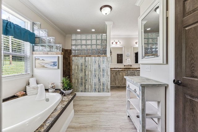 bathroom with crown molding, vanity, and a bath