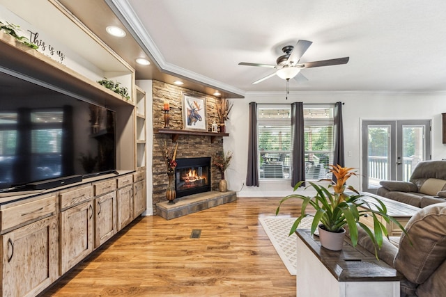 living area with light wood finished floors, a ceiling fan, ornamental molding, a fireplace, and recessed lighting