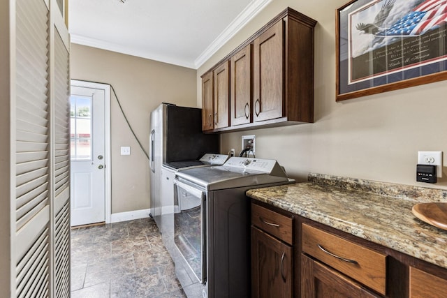 laundry room with crown molding, cabinet space, stone finish floor, washer and dryer, and baseboards