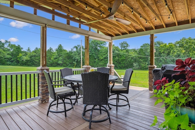 deck with outdoor dining area, a yard, and ceiling fan