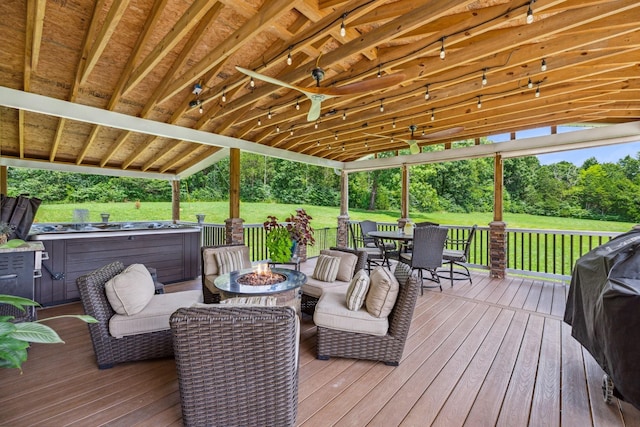 deck with an outdoor fire pit, a hot tub, a grill, and outdoor dining space