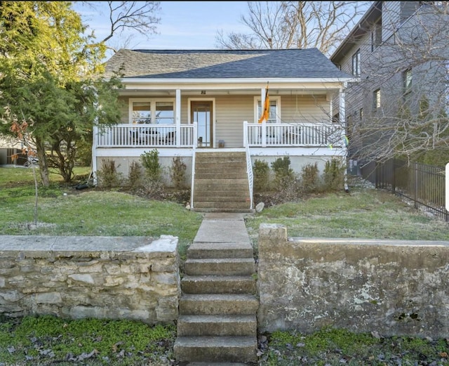 bungalow with stairway, roof with shingles, fence, a porch, and a front yard