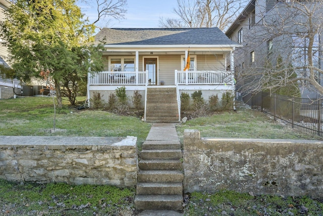 bungalow-style home featuring a porch, roof with shingles, stairs, fence, and a front lawn