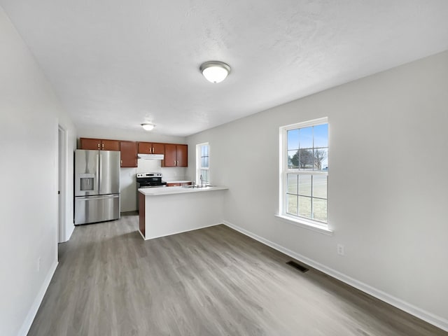 kitchen with a peninsula, stainless steel appliances, light countertops, a healthy amount of sunlight, and under cabinet range hood