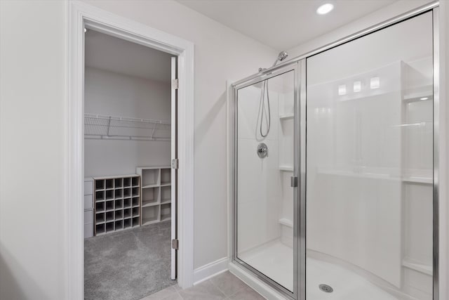 full bath featuring baseboards, a spacious closet, a shower stall, and tile patterned floors