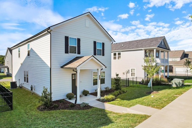 view of front of property with a balcony, fence, central AC unit, and a front yard