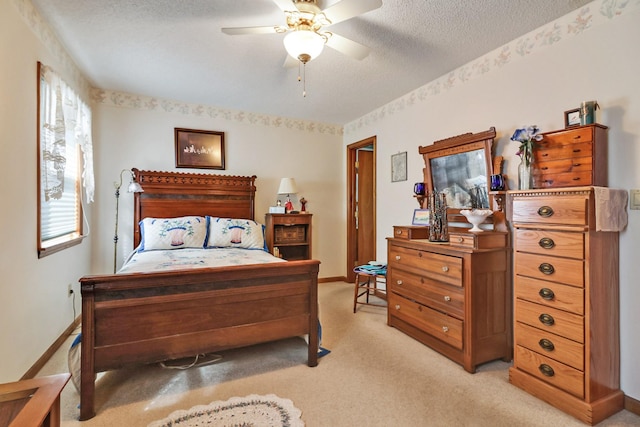 bedroom featuring a textured ceiling, baseboards, a ceiling fan, and light colored carpet