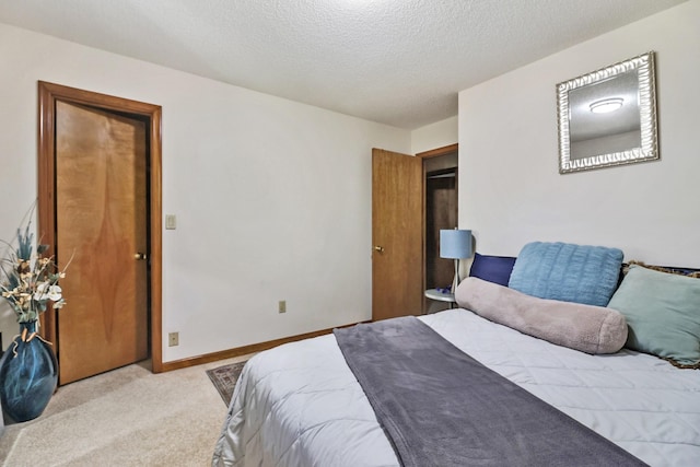 bedroom featuring light carpet, a textured ceiling, and baseboards