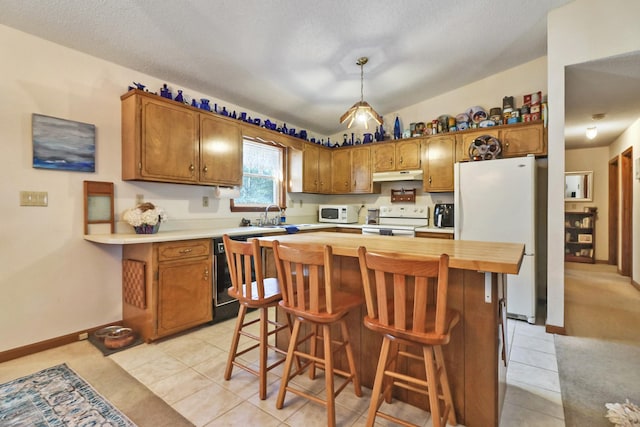 kitchen with brown cabinets, lofted ceiling, white appliances, under cabinet range hood, and a kitchen breakfast bar