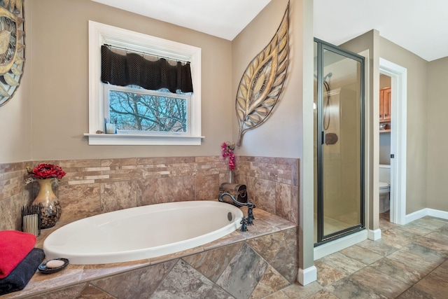 bathroom featuring toilet, a garden tub, a shower stall, and baseboards