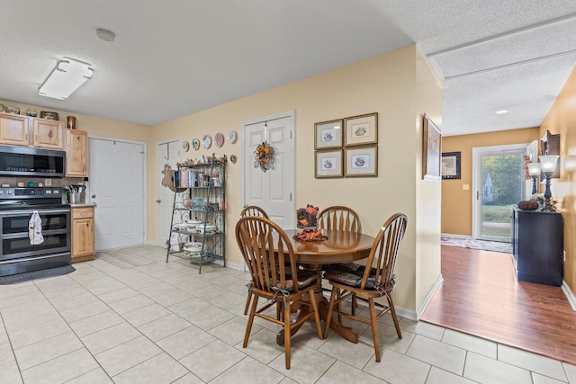 dining area featuring light tile patterned floors, baseboards, and a textured ceiling