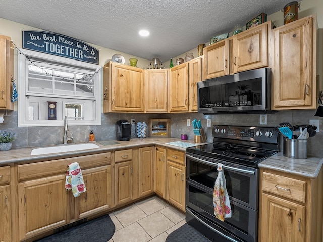 kitchen featuring range with two ovens, light tile patterned floors, light countertops, stainless steel microwave, and a sink