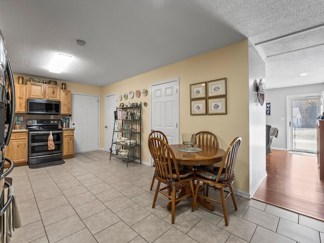 dining room with a textured ceiling, baseboards, and light tile patterned floors