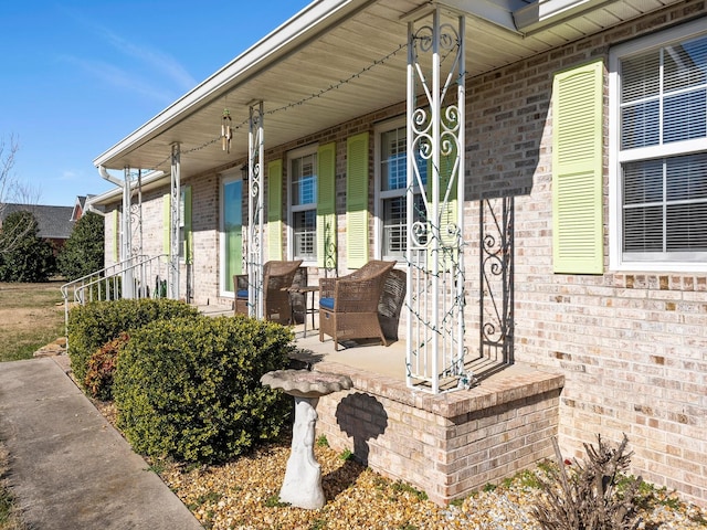 view of exterior entry featuring a porch and brick siding