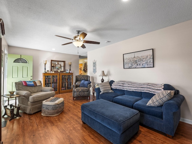 living room with ceiling fan, a textured ceiling, baseboards, and wood finished floors