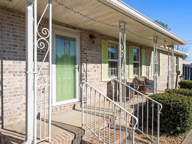 entrance to property featuring covered porch and brick siding